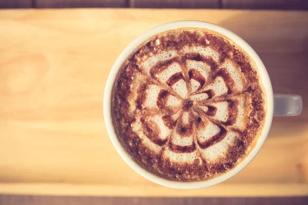 A Latte Coffee art on the wooden desk vintage color