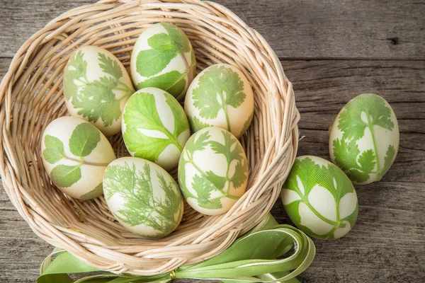 Œufs de Pâques dans le panier sur des planches rustiques en bois — Photo