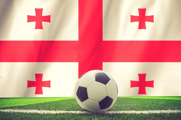 Balón de fútbol y bandera nacional de Georgia se encuentra en la hierba verde — Foto de Stock