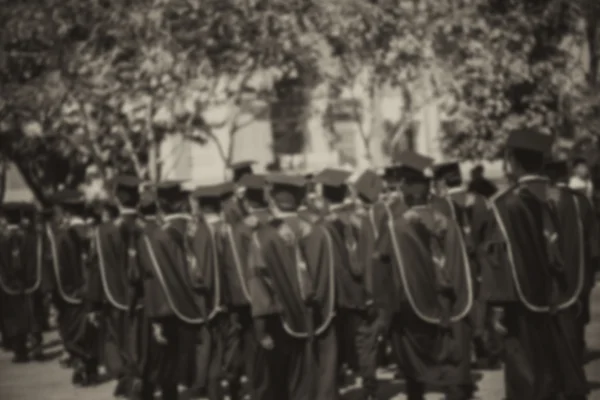 Los graduados borrosa están caminando en línea para obtener su título, monótono —  Fotos de Stock