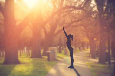 Pratik Yoga Parkı üzerinde günbatımında siluet genç kadın.