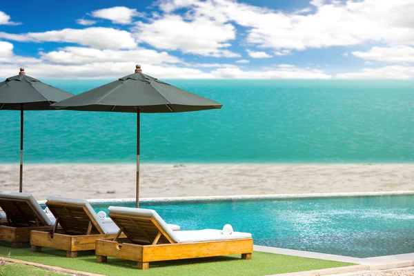 Niewyraźne, błękitne morze i biały piasek z plaży parasol, leżak — Zdjęcie stockowe