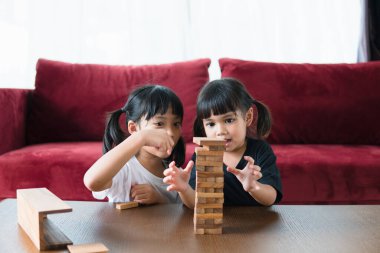 İki Asyalı kız evde ahşap destelerle oynuyorlar.