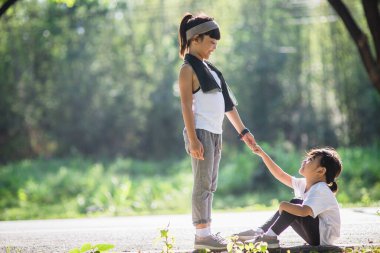 Tatlı Asyalı kız, koşarken kız kardeşine yardım etmek için elini uzat.