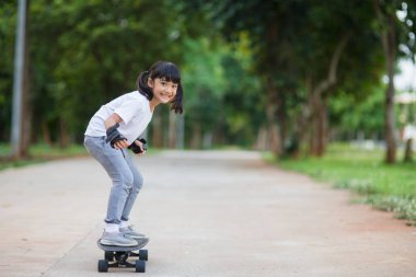 Şirin küçük kız kaykay ya da kaykay parkında kayıyor.