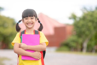 Back to school. cute asian child girls with school bag holding a book together in the school