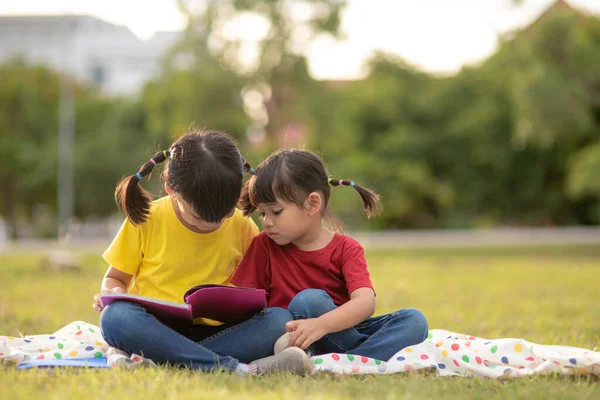 Two Beautiful Little Girls Reading Books Garden Sitting Grass Concept — Zdjęcie stockowe