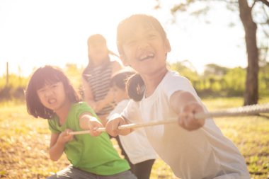 Children playing tug of war at the park on sunsut