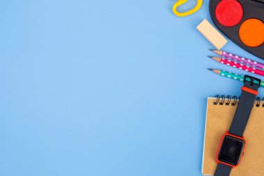 Mavi arka planda kırtasiye aksesuarı. Okul malzemeleri, kalemler, boyalar ve renkli kitaplar. Mavi arka planda fotokopi alanı var. Eðitim ve serbest çalýþma kavramı