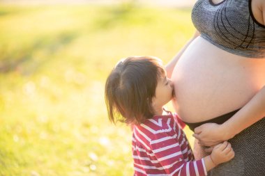 Mutlu bir aile, hamile bir anne ve gün ışığında küçük bir kız çocuğu.