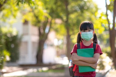 Coronavirus ve grip salgını sırasında maske takan okul çocuğu. Kardeş kız karantina ve tecritten sonra okula geri dönüyor. Koronavirüsü önleme maskeli çocuklar. Odaklan.