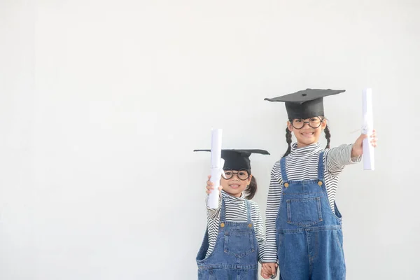 Siblings children girl graduation with cap and diploma over white.