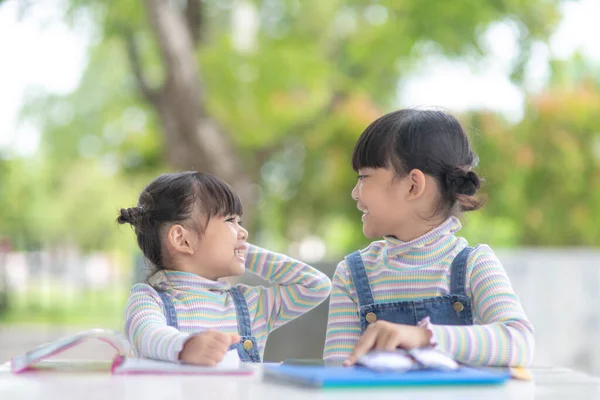 两个亚洲学生小女孩正在看桌上的书 — 图库照片