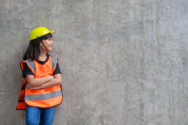 Yansıtıcı tişörtler giyen Asyalı kız ve sarı bir şapka. Öğrenmeye ve geliştirmeye, küçük mimar..