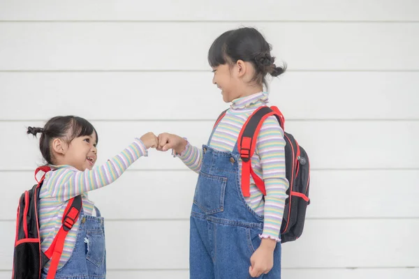 回学校去两个可爱的亚洲女孩 背着书包 拿着一本白色背景的书 — 图库照片