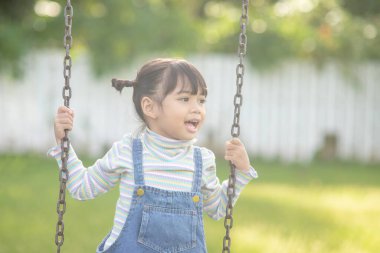 Parkta salıncakta sallanan mutlu küçük Asyalı kız
