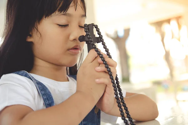 亚洲小女孩抱着基督教的十字架祈祷 — 图库照片
