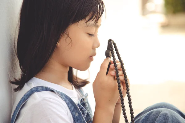 亚洲小女孩抱着基督教的十字架祈祷 — 图库照片