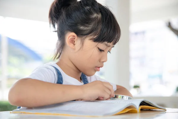 Menina Asiática Lendo Livros Mesa Com Uma Lupa — Fotografia de Stock