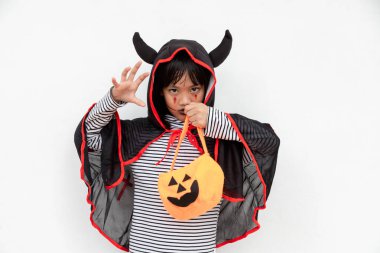 Komik cadılar bayramı çocuğu konsepti, Cadılar Bayramı hayaleti kostümlü küçük tatlı kız. Elinde beyaz arka planda turuncu balkabağı hayaleti tutuyor.