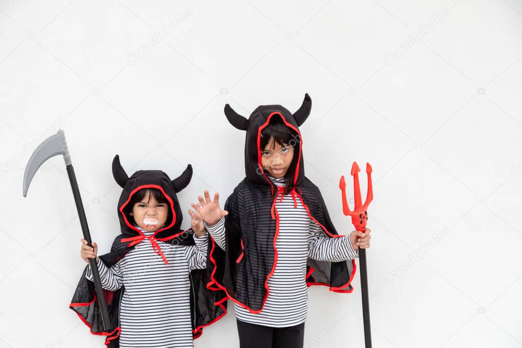 Happy sibling girls at the Halloween party. Children wearing costumes Halloweens. Concept of children ready for a party.