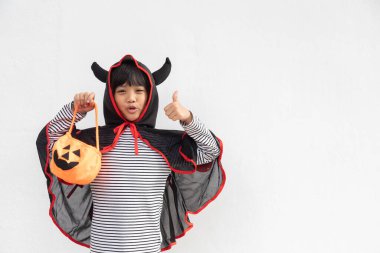 Komik cadılar bayramı çocuğu konsepti, Cadılar Bayramı hayaleti kostümlü küçük tatlı kız. Elinde beyaz arka planda turuncu balkabağı hayaleti tutuyor. 