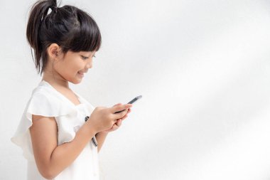 Küçük bir kız telefona odaklanmış, akıllı telefona bakın, çocuklar için teknoloji konsepti, profil görüntüsü, beyaz arka planda izole edilmiş, kopyalama alanı