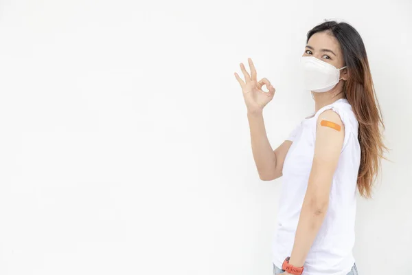 アジアの女性は腕に包帯を表示します 白い背景でワクチンを受けた後の幸せなアジアの女性は良い感じ — ストック写真