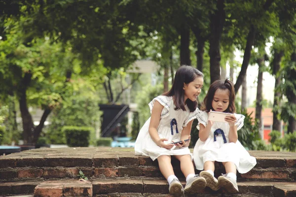 Crianças Conceito E Gadgets. Duas Meninas Irmãs Irmãos Olhar Para