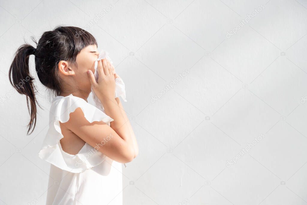 Asian child girl sick with sneezing on the nose and cold cough on tissue paper because weak or virus and bacteria from dust weather 