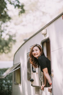 Mutlu, güzel Asyalı kadın, karavan penceresinin yanında.