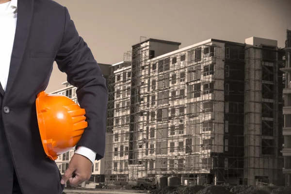 Ingeniero sosteniendo casco naranja para la seguridad de los trabajadores en contructi — Foto de Stock