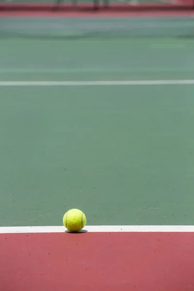 Tennisboll på domstolen med nätet i bakgrunden — Stockfoto