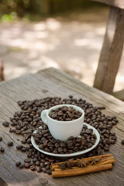 Taza de café y grano de café en una mesa de madera — Foto de Stock