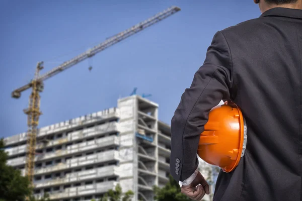 Ingeniero sosteniendo casco naranja para la seguridad de los trabajadores en construcción —  Fotos de Stock