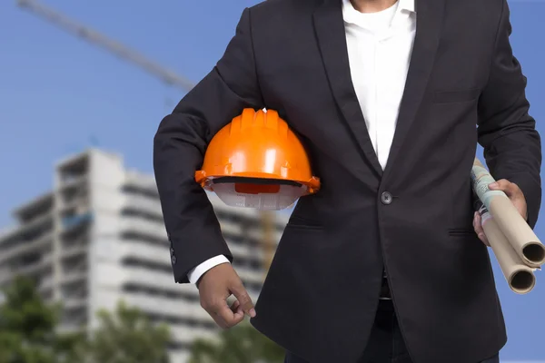 Engenheiro com capacete laranja e Blueprint na construção backgr — Fotografia de Stock