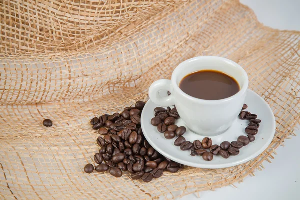 Xícara de café e grãos em um fundo branco. — Fotografia de Stock