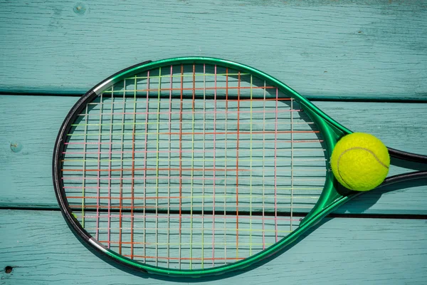 A tennis racket with tennis ball on green wood texture — Stock Photo, Image