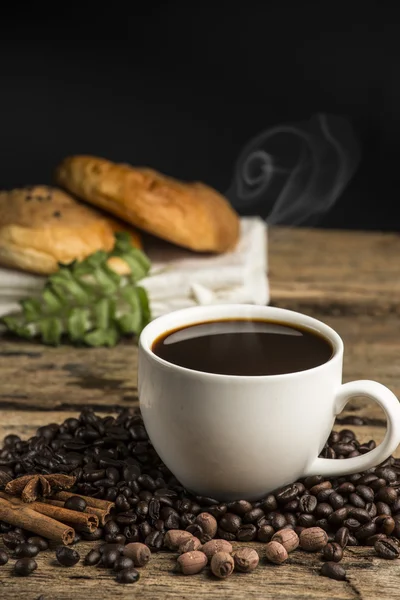 Xícara de café quente em uma mesa de madeira velha com grão de café e bi — Fotografia de Stock