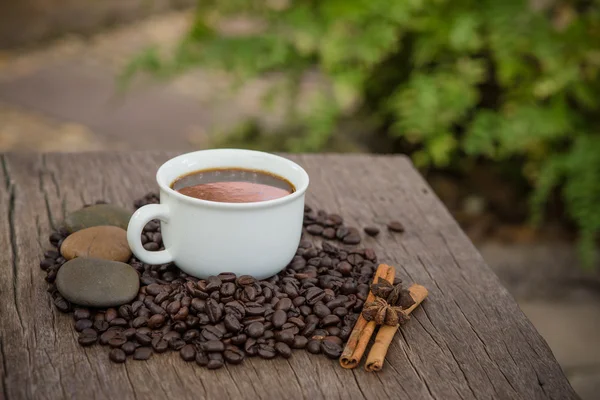 Tasse à café et grains de café sur une table en bois — Photo