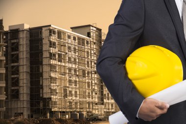 işçi güvenliği için sarı kask contructi üzerinde tutan mühendisi