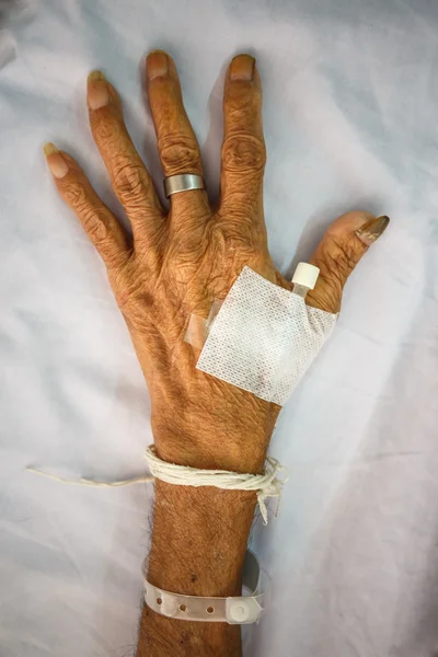 Mano del viejo paciente con tapón en la cama en el hospital — Foto de Stock