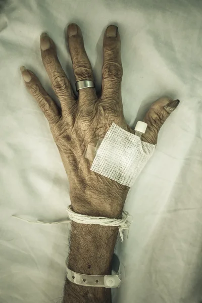 Hand of old patient with plug on bed in hospital — Stock Photo, Image