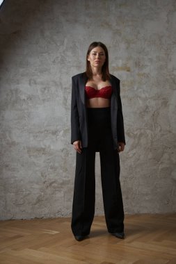 Siyah takım elbiseli, iç mekânda kırmızı sutyen takan güzel, genç bir esmer.