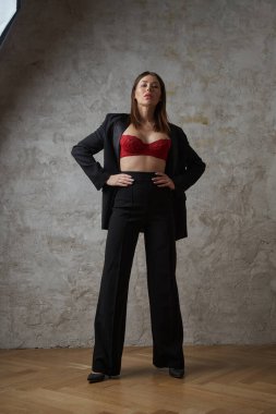 Siyah takım elbiseli, iç mekânda kırmızı sutyen takan güzel, genç bir esmer.