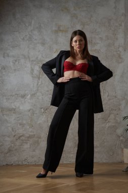 Siyah takım elbiseli, iç mekânda kırmızı sutyen takan güzel, genç bir esmer.