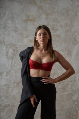 Siyah takım elbiseli, iç mekânda kırmızı sutyen takan güzel, genç bir esmer.