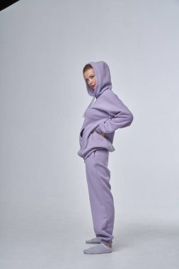 Beyaz stüdyo arka planında duran mor spor elbiseli sarışın güzel kadının stüdyo portresi. 