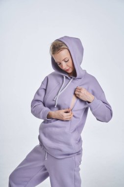 Beyaz stüdyo arka planında duran mor spor elbiseli sarışın güzel kadının stüdyo portresi. 