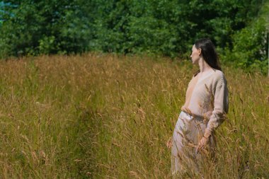 Genç bir kadın yaz sıcağının ortasında bir tarlada kuru otların arasında.